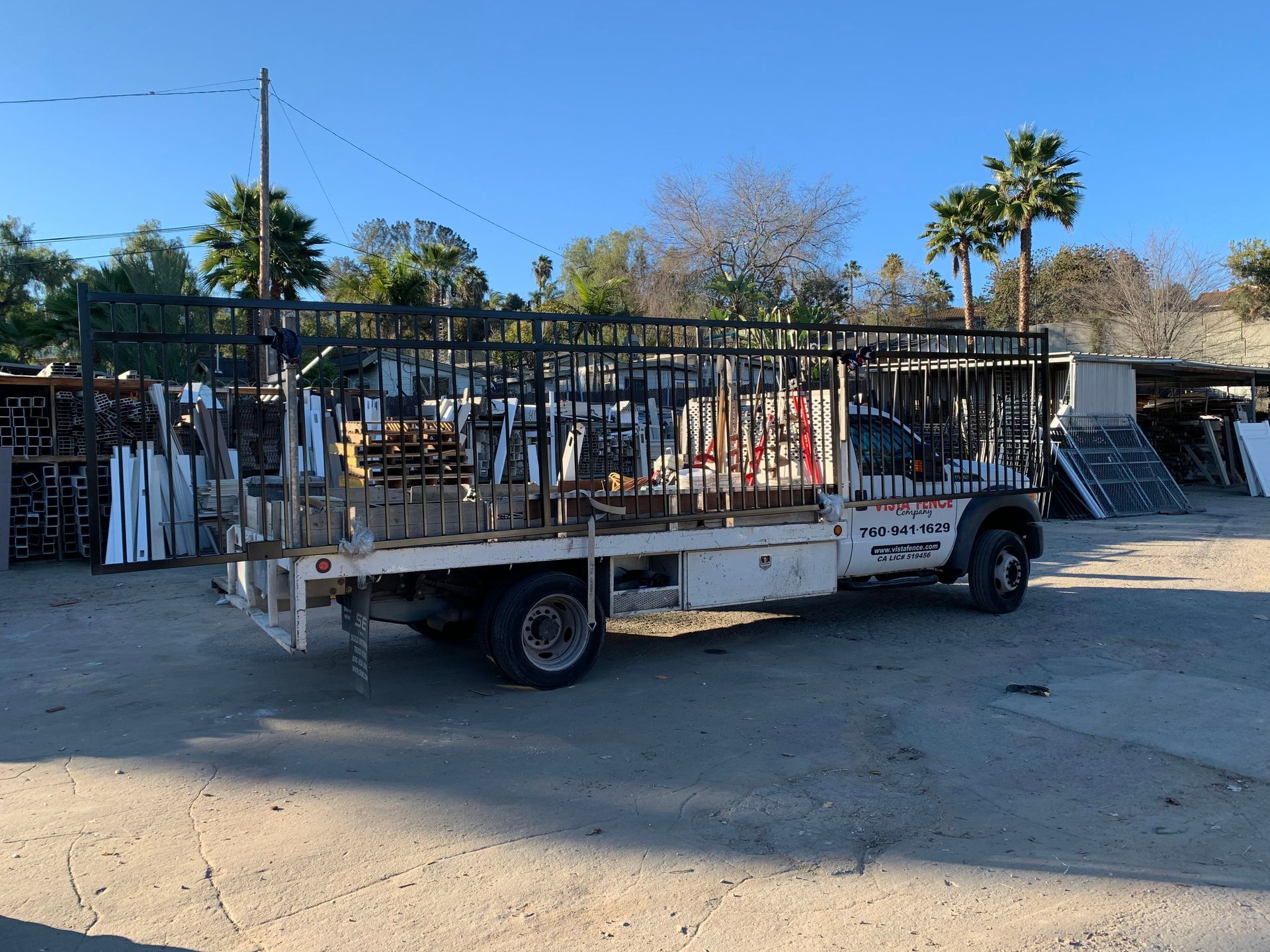 A white truck with a flat bed is parked in a parking lot.