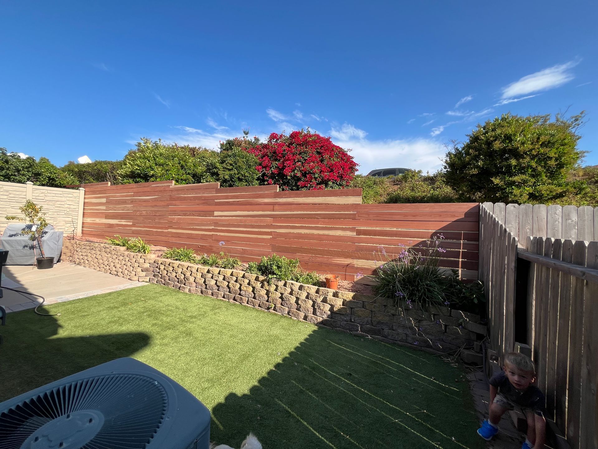A backyard with a fence and a large air conditioner.