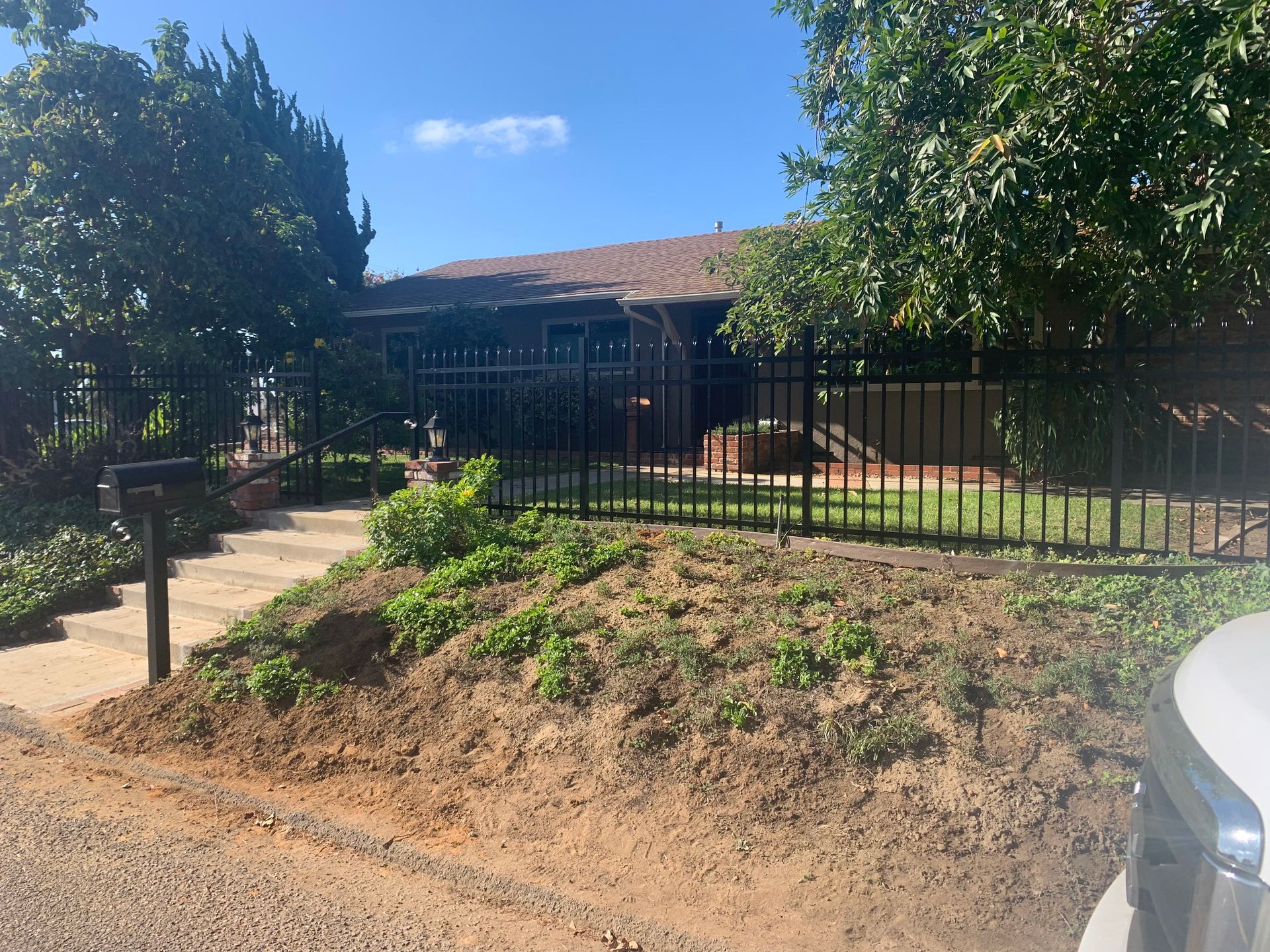 A car is parked in front of a house with a fence around it.