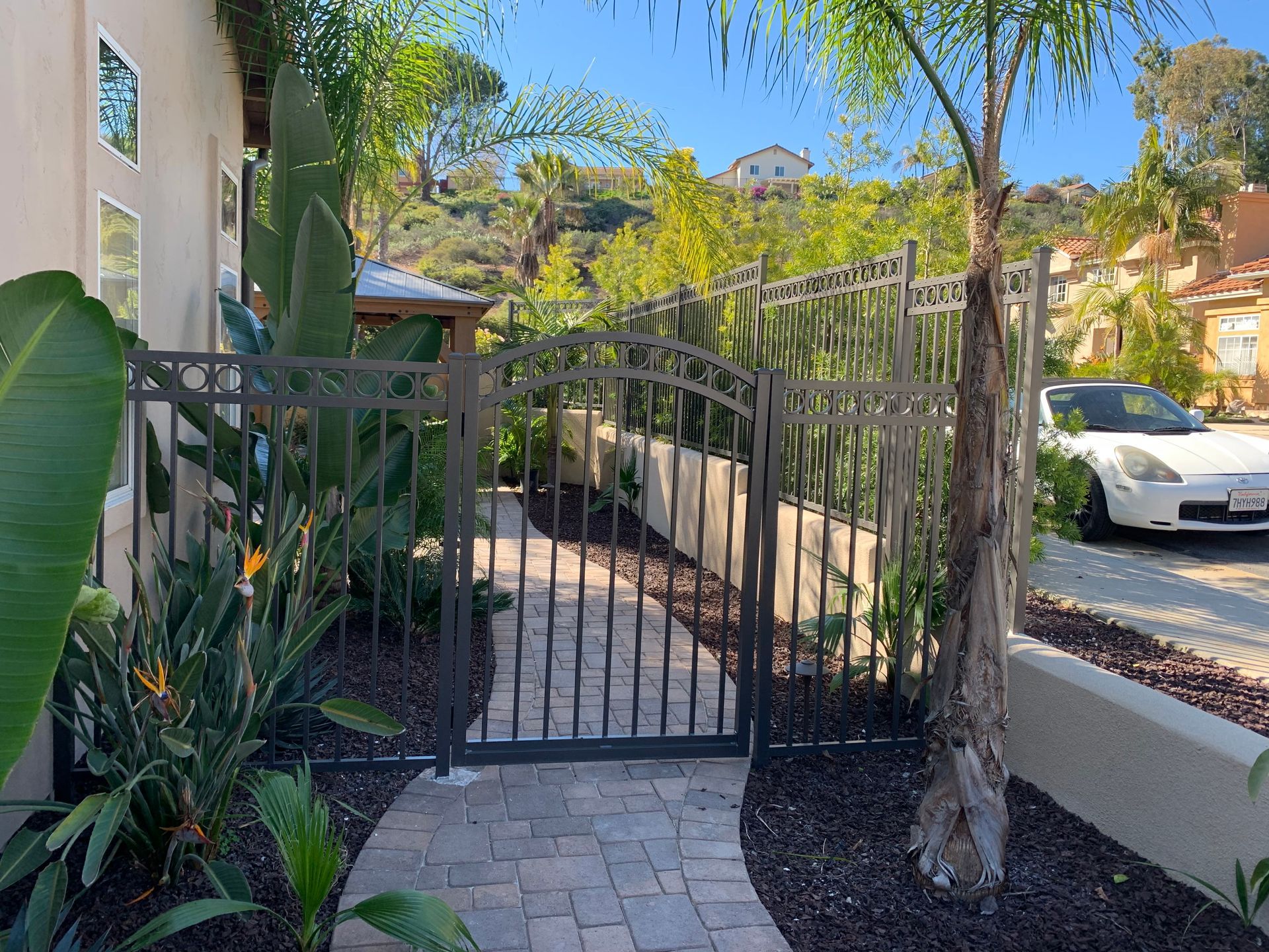 A white car is parked behind a gate in front of a house.