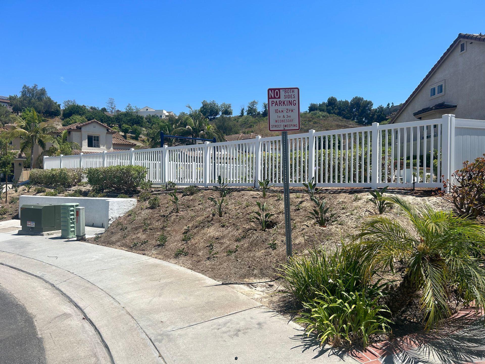 A white fence with a no parking sign in front of it.