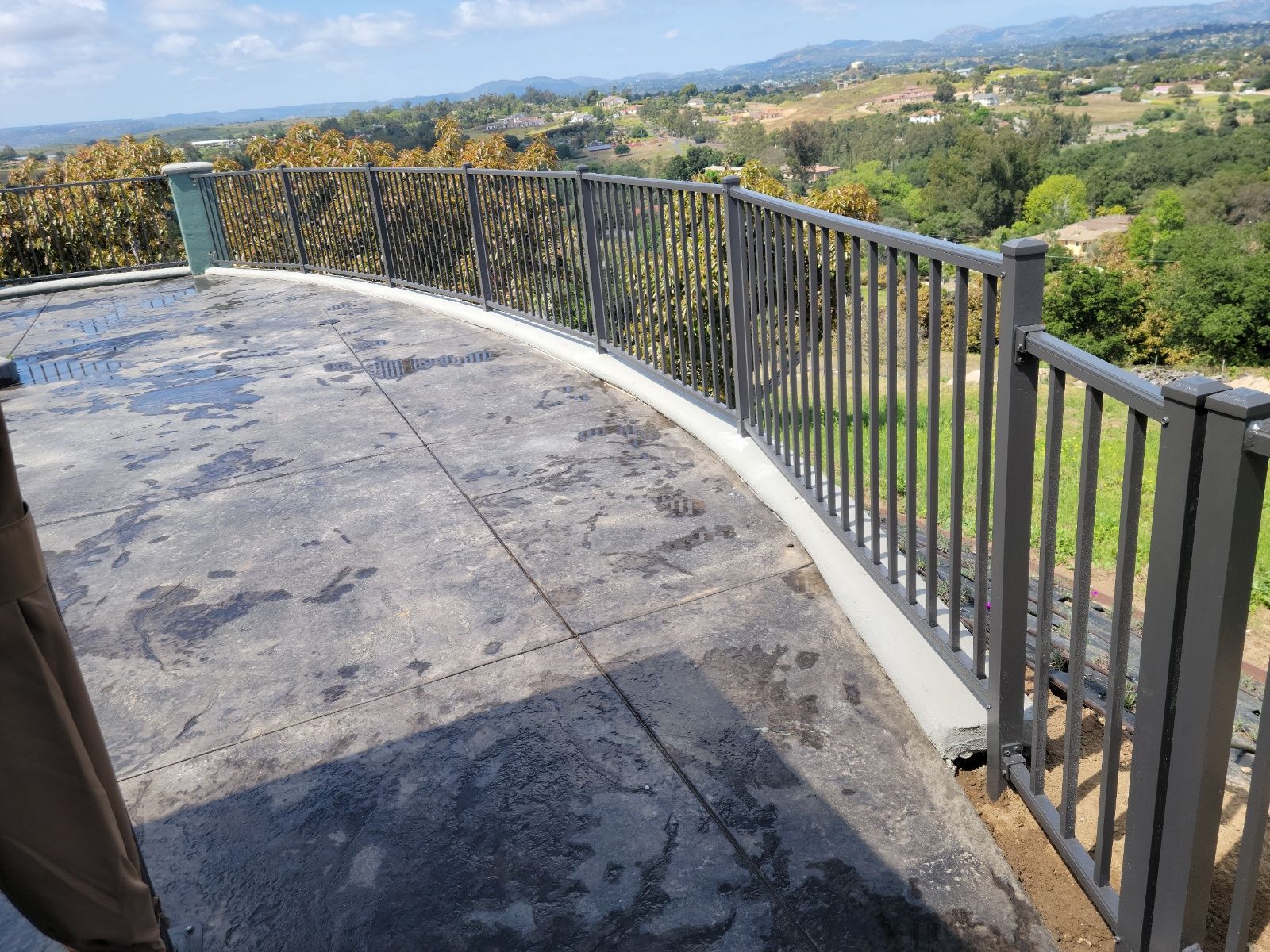 A balcony with a fence and a view of a valley.