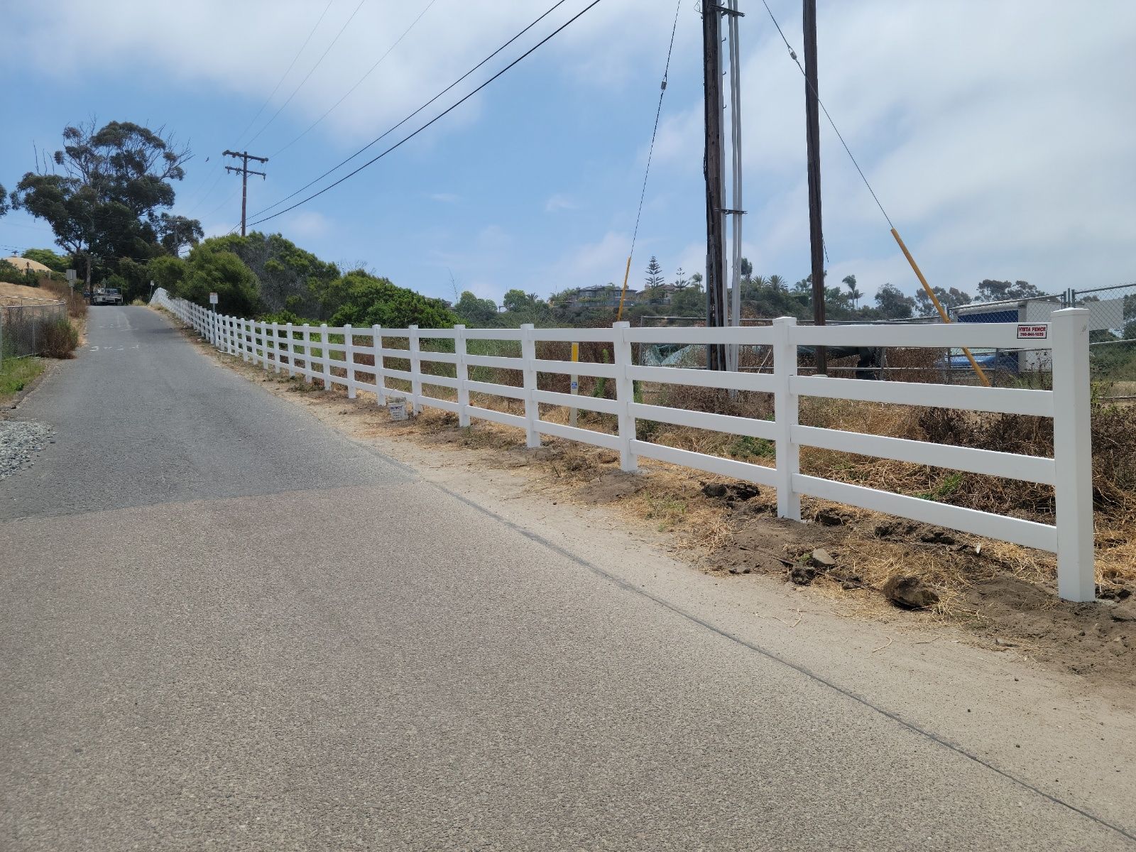 A white fence along the side of a road.
