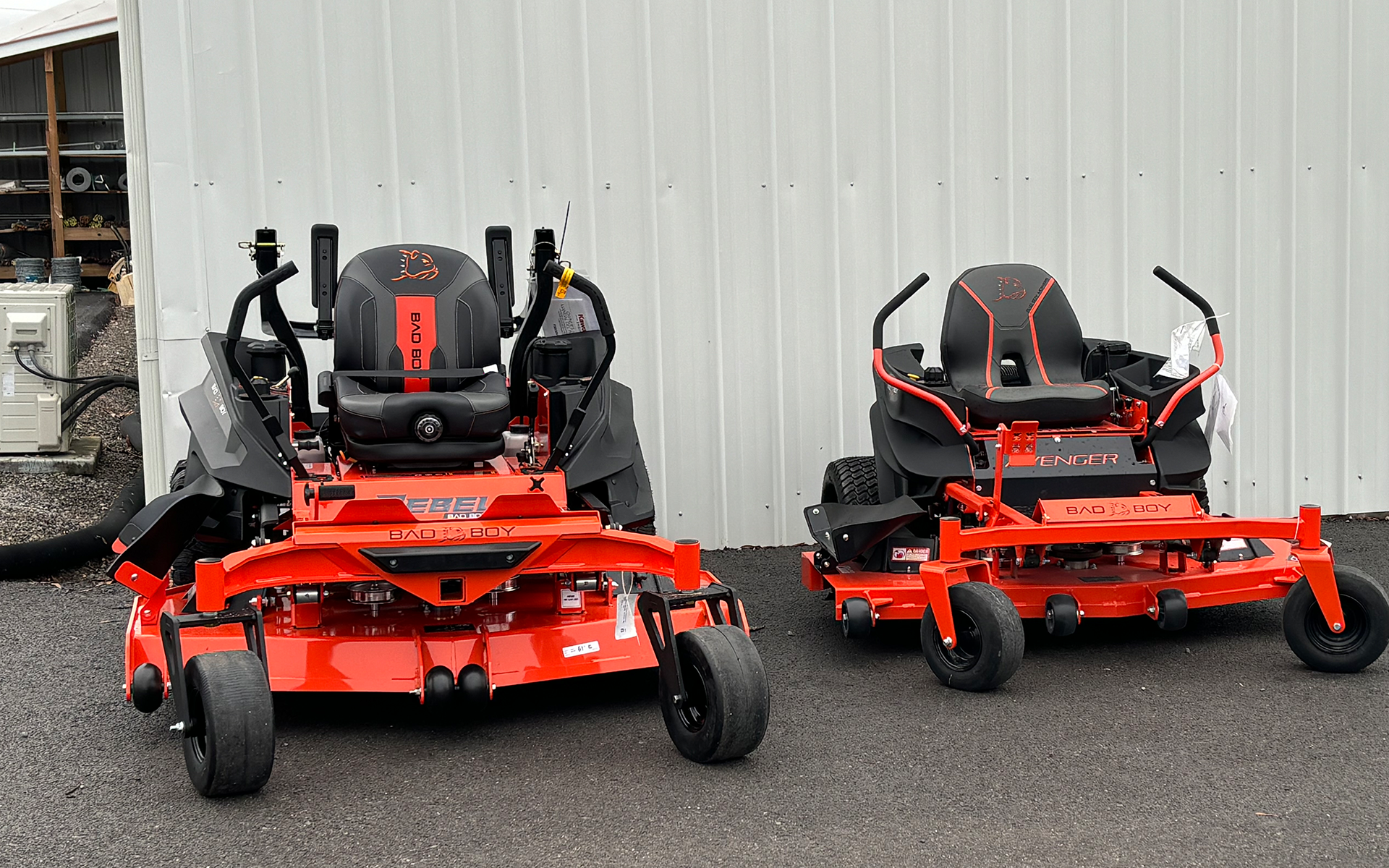 two red lawn mowers are parked next to each other in front of a white building 