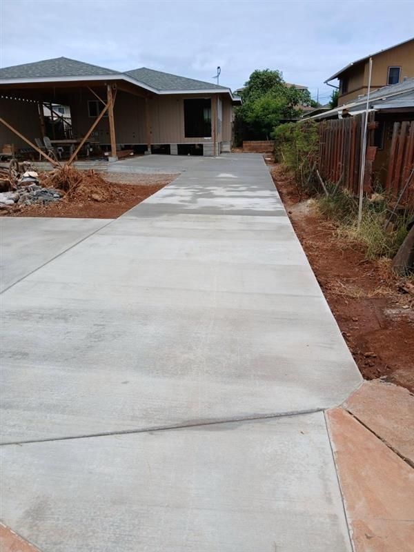Backyard patio, a white house, and an orange hose on the concrete.