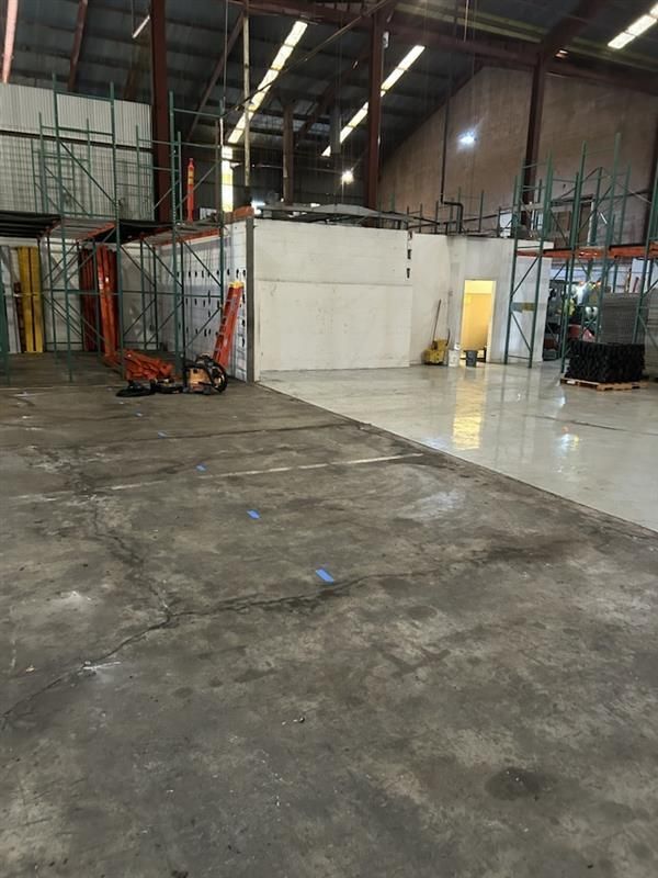Covered patio beside grassy yard and apartment building, with trash bin, window AC units, and white support post