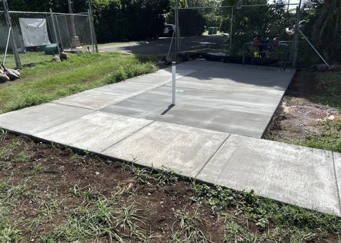 Outdoor concrete patio with a central metal pole and grassy yard around it