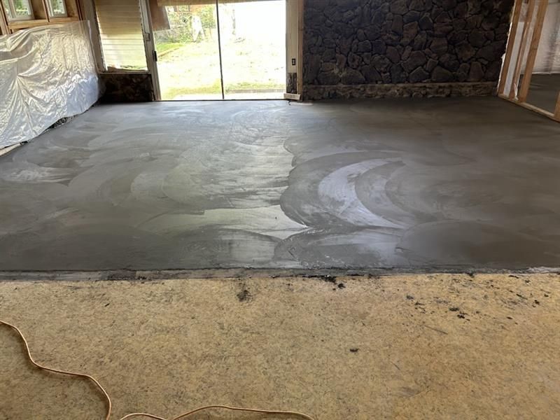 Unfinished concrete floor in a room with stone wall and sliding glass doors to the outside