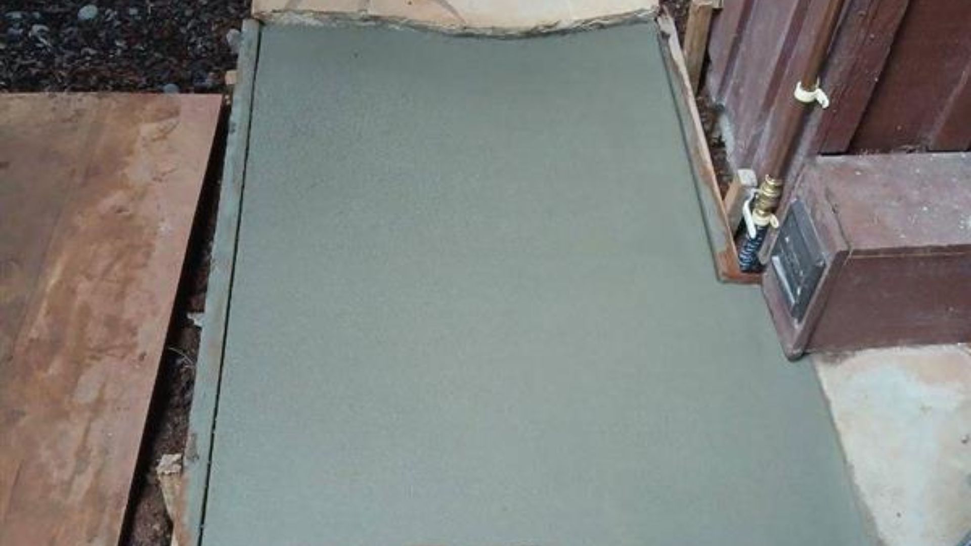 Freshly paved gray walkway between wooden structures outdoors