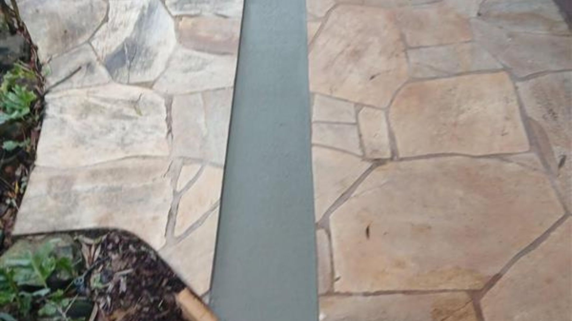 Stone walkway with a narrow gray concrete strip running between two tan rock surfaces.