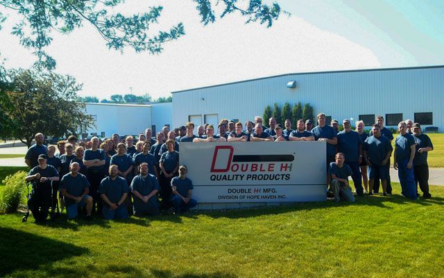 Group photo of employees in front of a Double HH Quality Products sign and building.