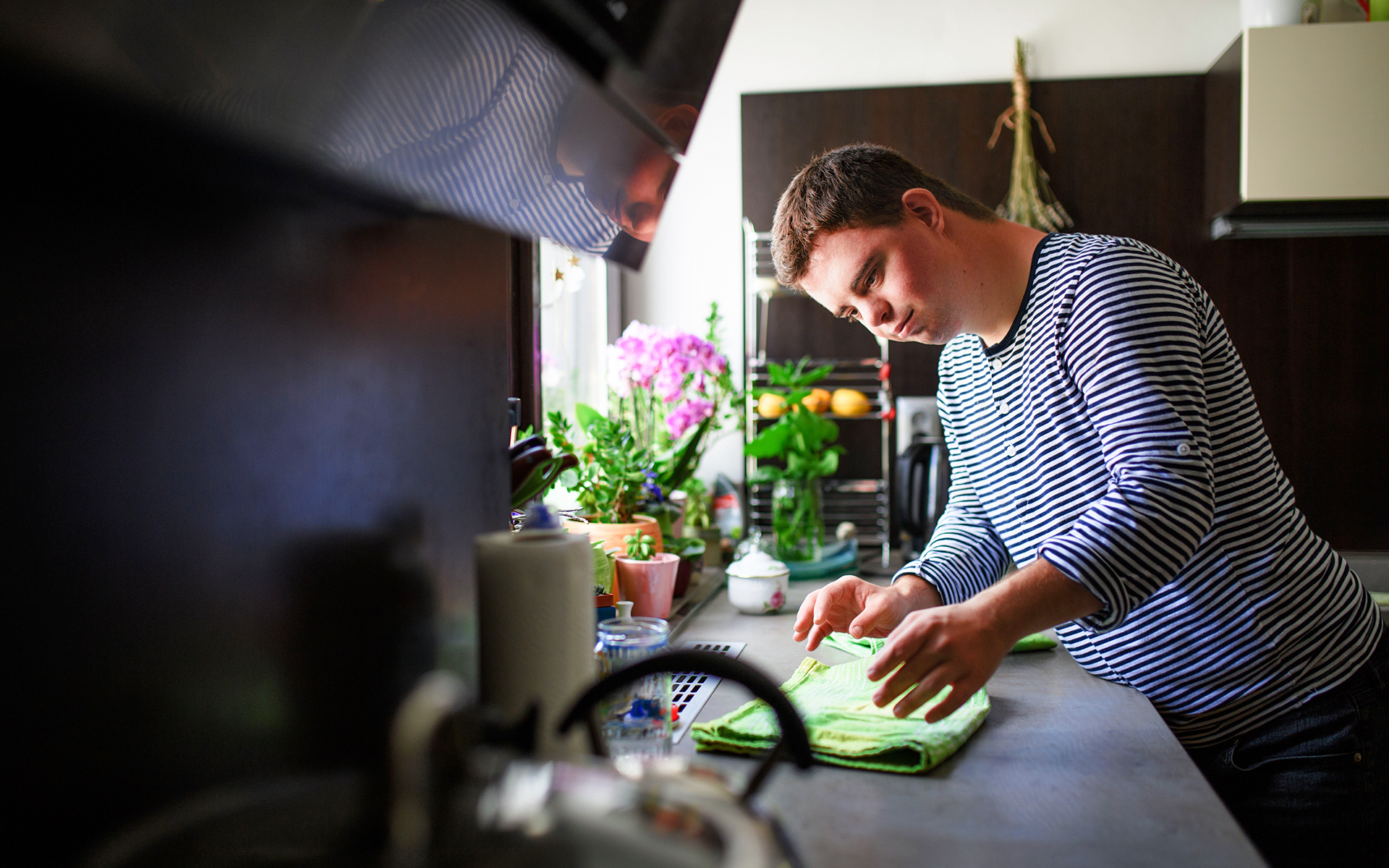A man is standing at a kitchen counter folding napkins.