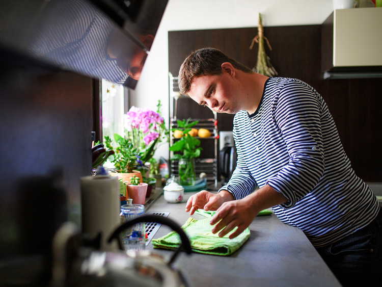 A man is standing at a kitchen counter folding napkins.