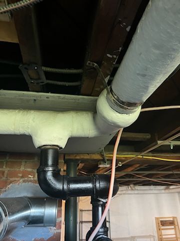 A black pipe is sitting on a checkered floor next to a brick wall.