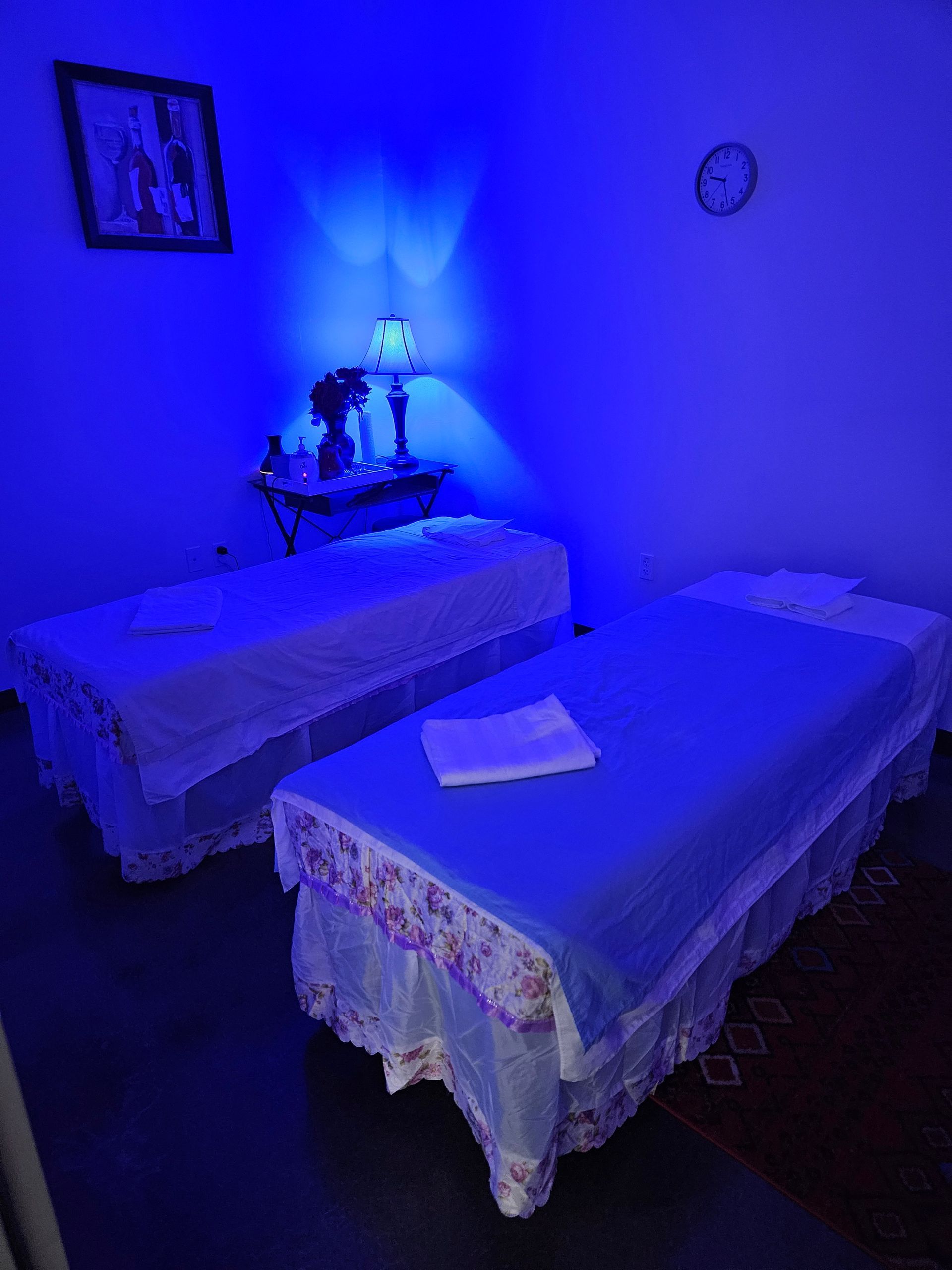 Two massage beds in a room with blue lights