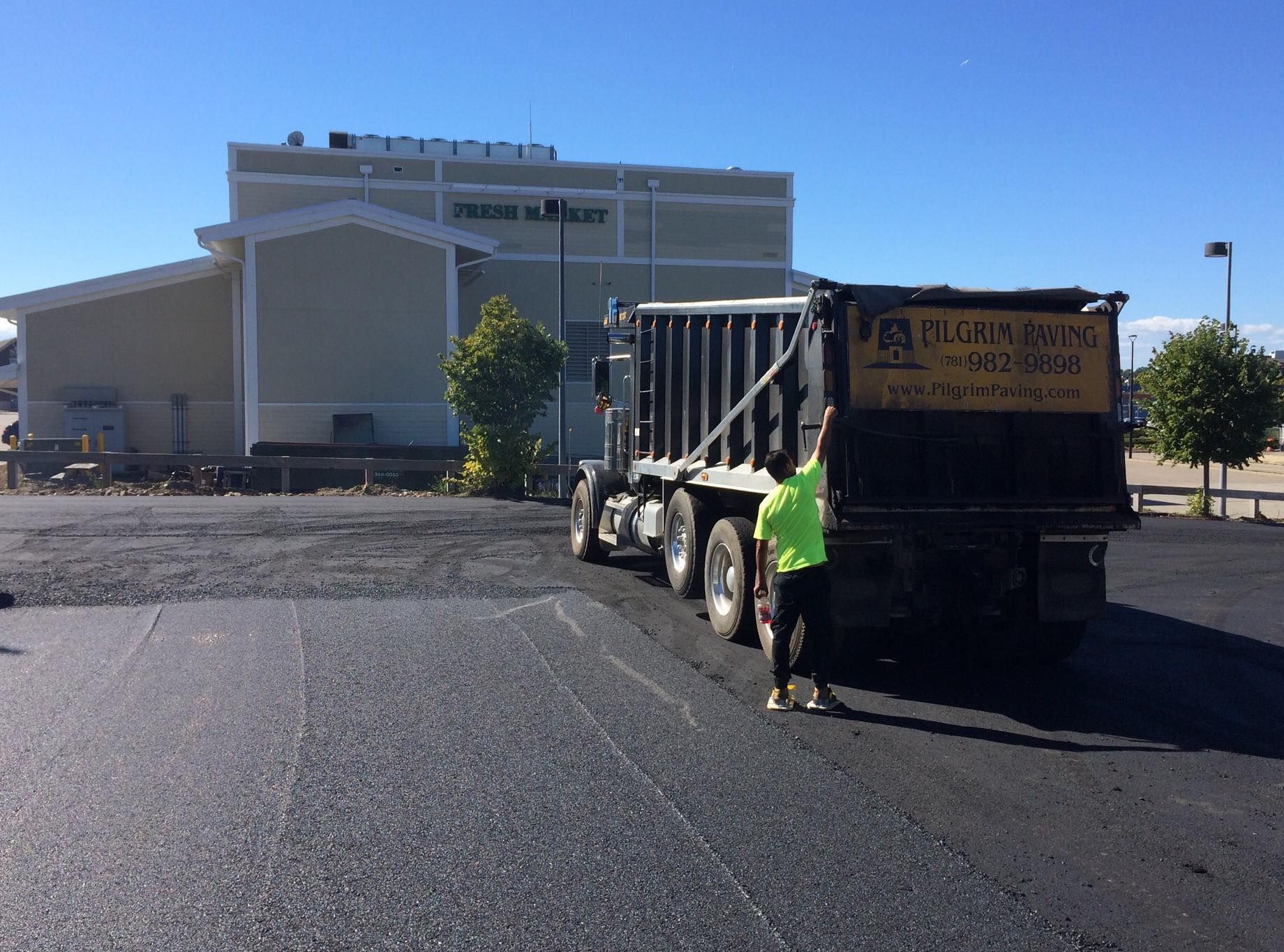 a dump truck is being loaded with asphalt in a parking lot