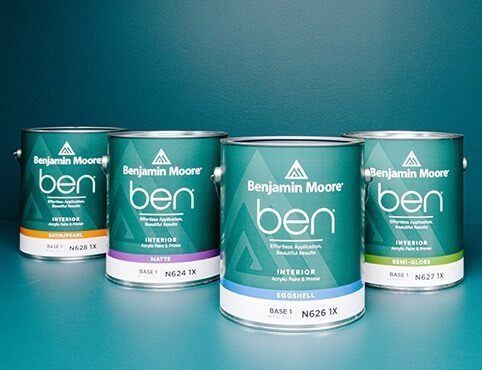 Four cans of benjamin moore paint are lined up on a table.