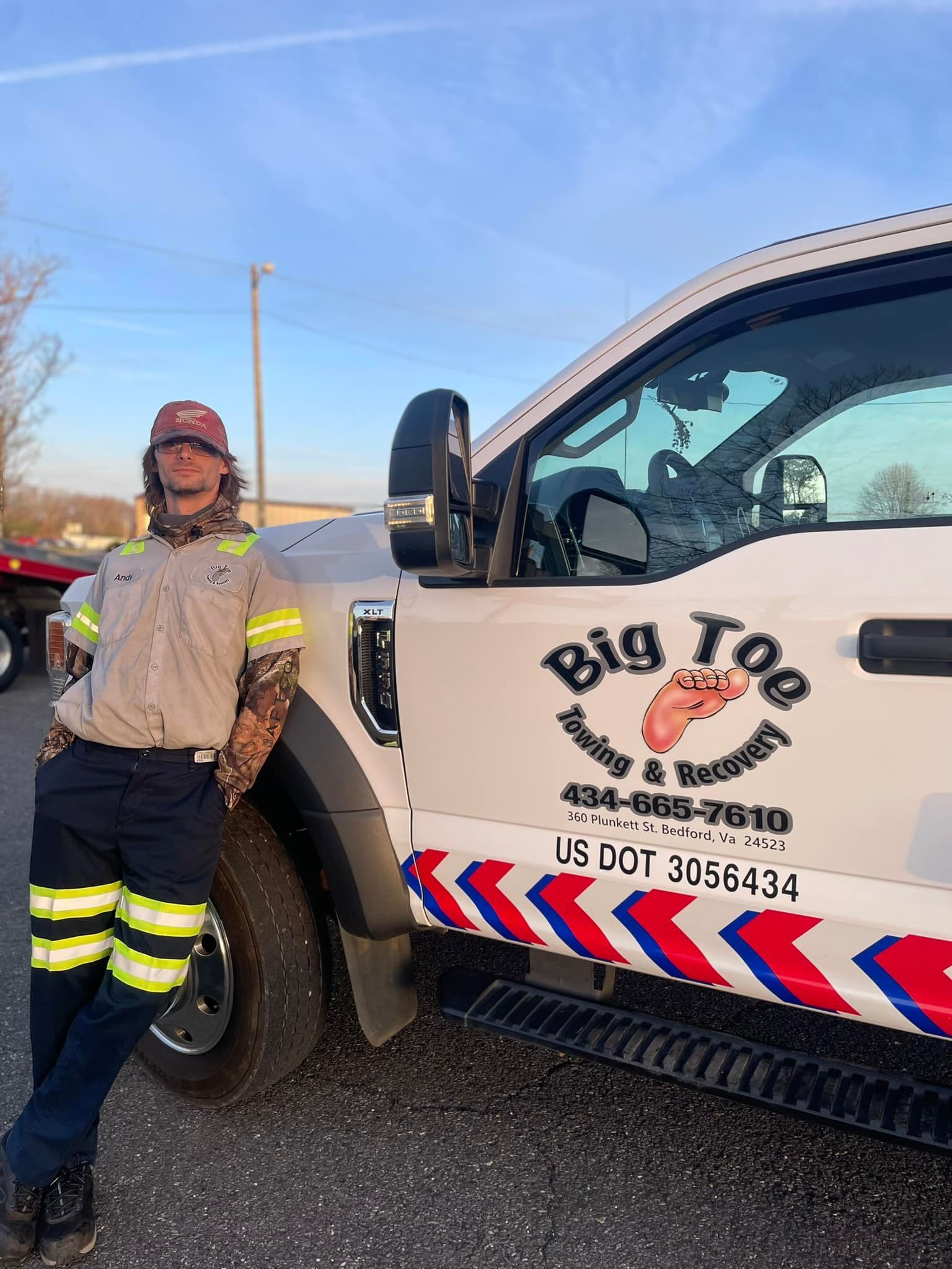 A man is standing next to a tow truck.