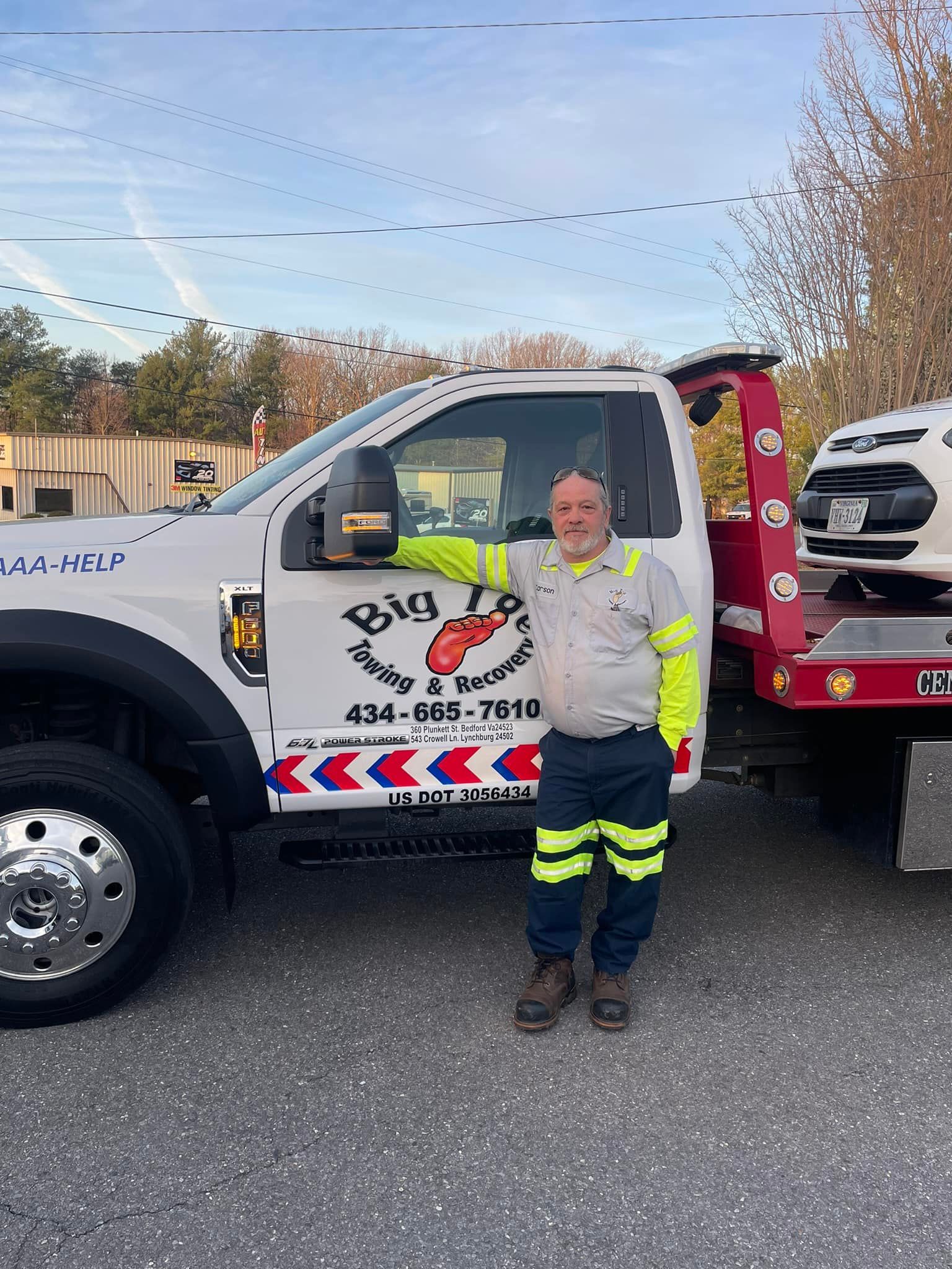 A man is standing in front of a tow truck.