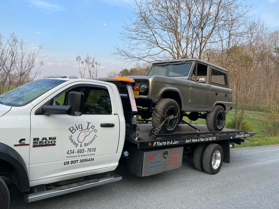 A tow truck is carrying a jeep on the back of it.