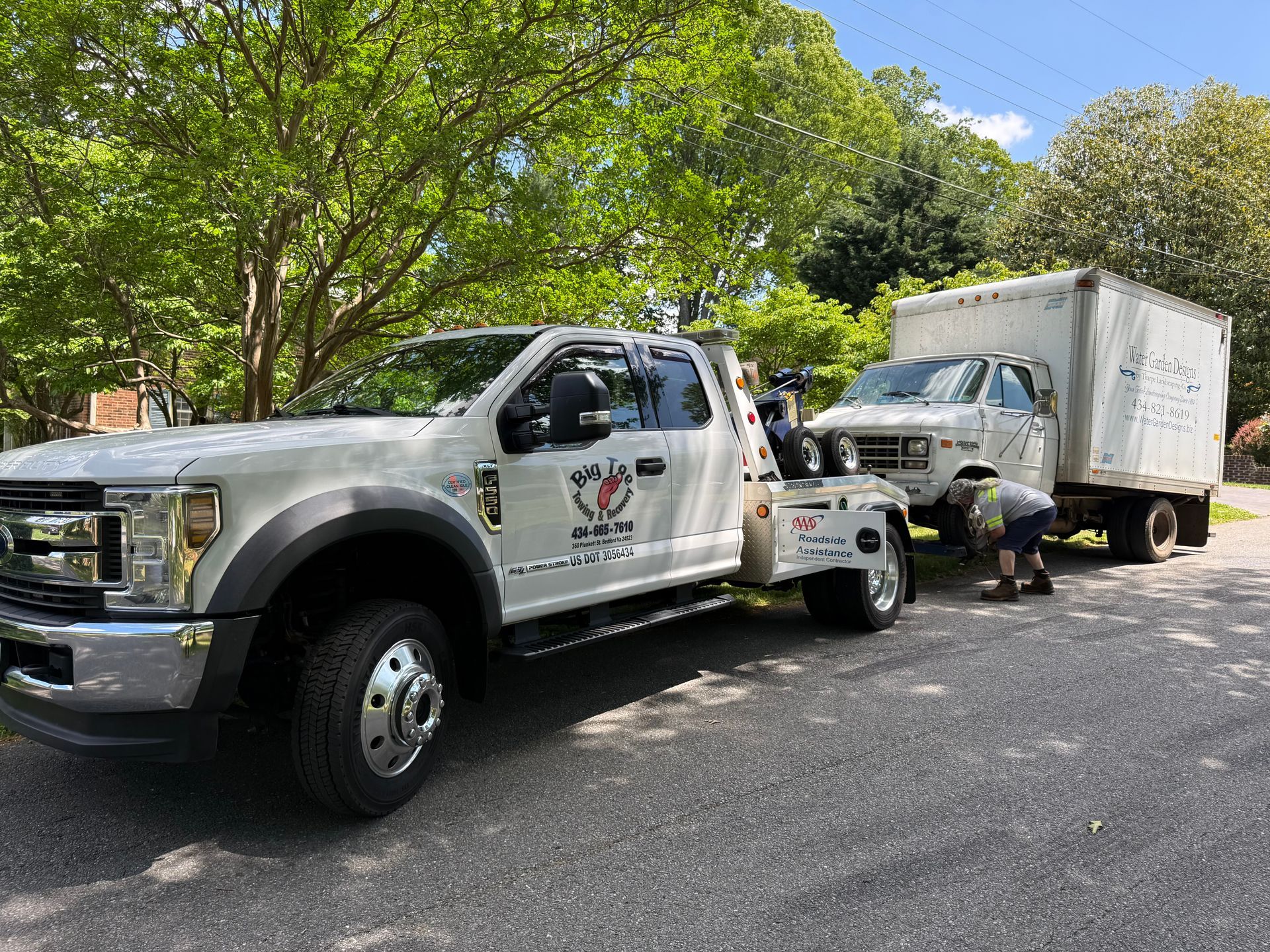 Two tow trucks are parked next to each other on the side of the road.