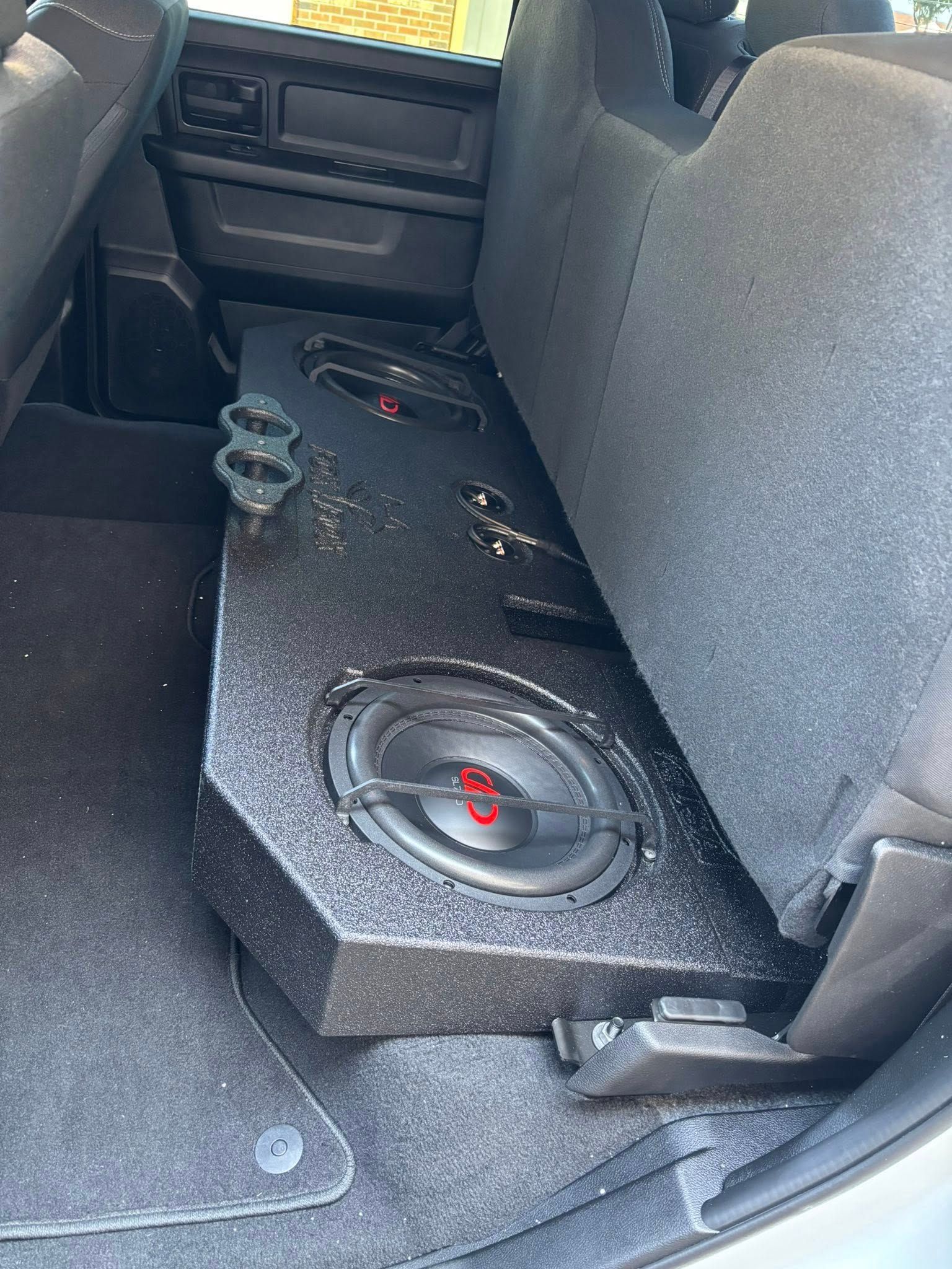 Car's rear interior with a black subwoofer box containing two subwoofers.