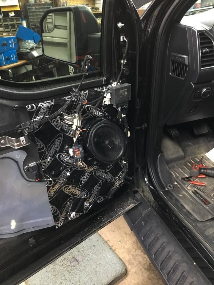 Car door with sound-dampening material and speaker visible during an audio system installation.
