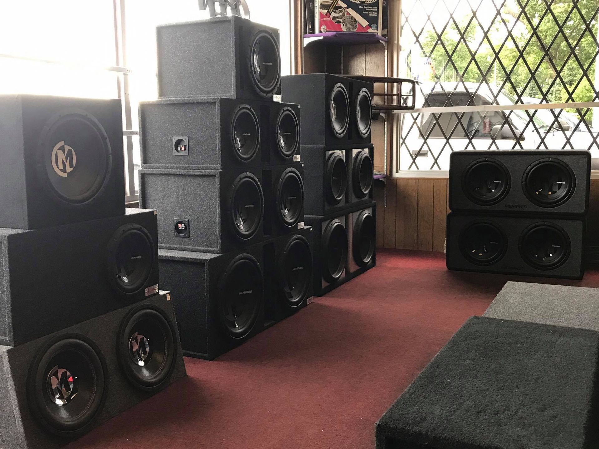 A room filled with many stacked black subwoofers for sale in a shop.