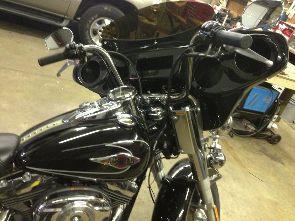 Black Harley-Davidson motorcycle with ape hanger handlebars, fairing, and chrome accents in a garage setting.