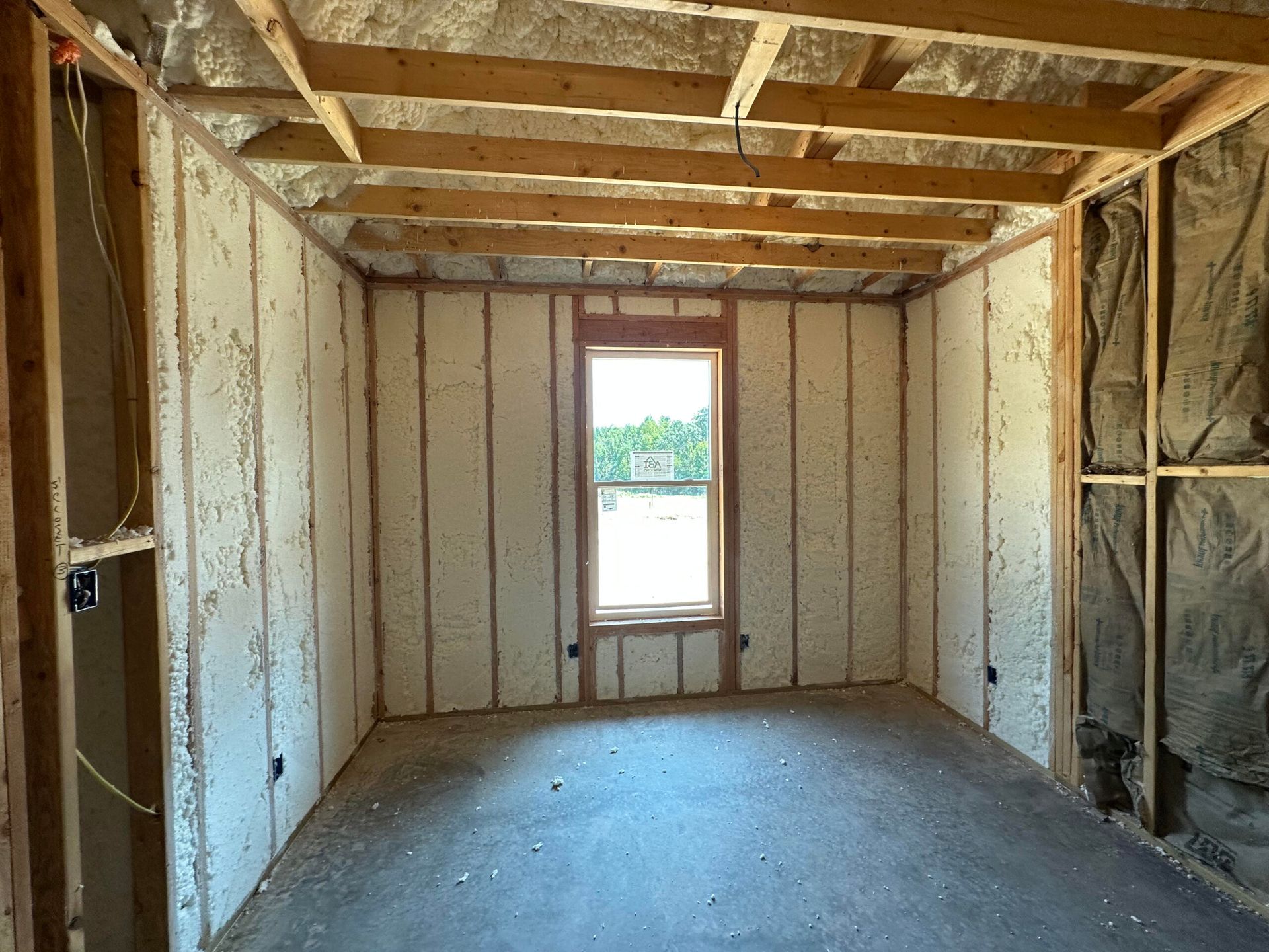 Interior of a room under construction, with exposed wood framing and insulation.