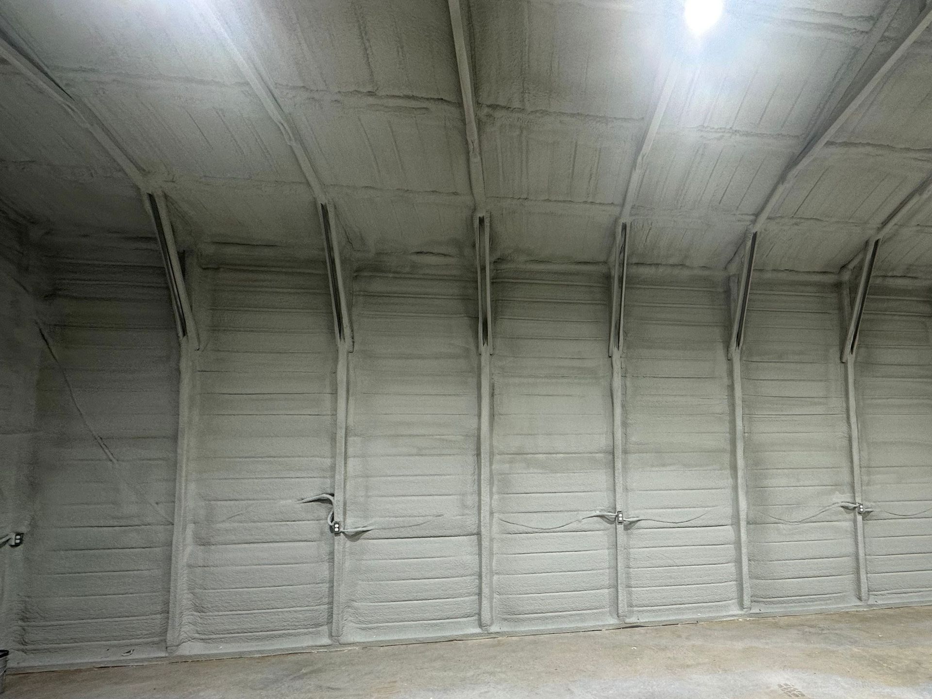 Interior of a large, gray concrete building with arched ceiling and vertical supports.