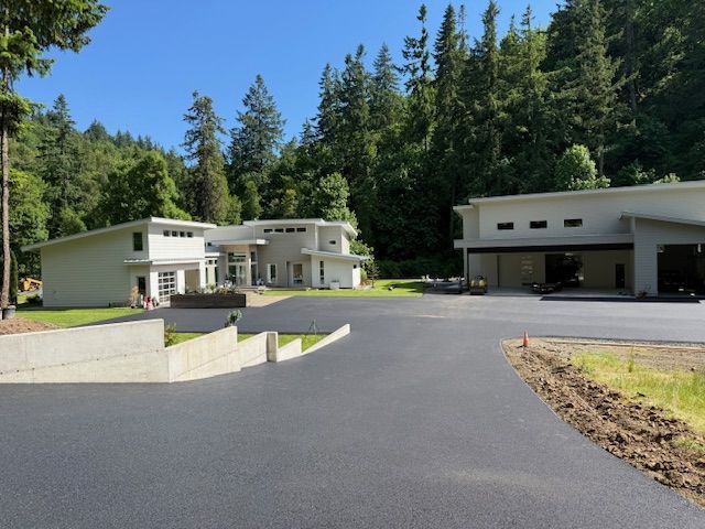 A driveway leading to a house with trees in the background