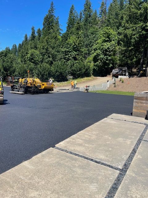 A yellow truck is driving down a road with trees in the background.