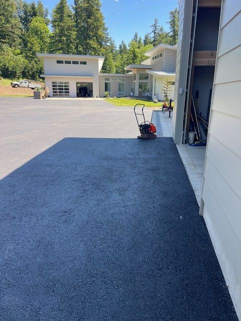 A black asphalt driveway with a house in the background