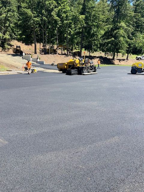 A group of construction workers are laying asphalt in a parking lot.