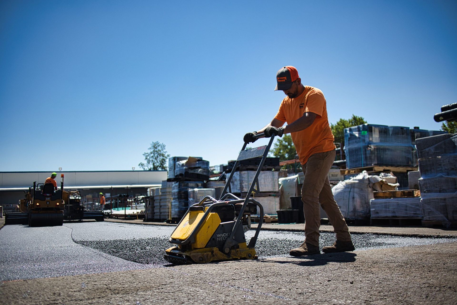 A man is using a machine to compact gravel in a parking lot.