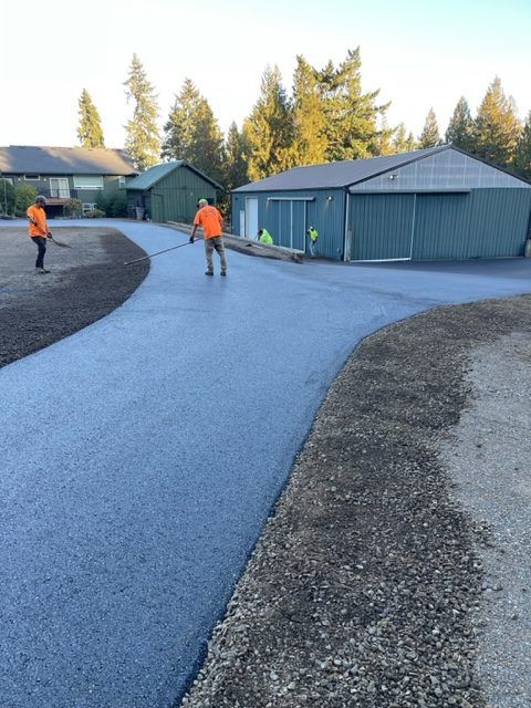 Two men are working on a driveway in front of a house