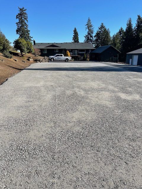 A white truck is parked in a gravel driveway in front of a house