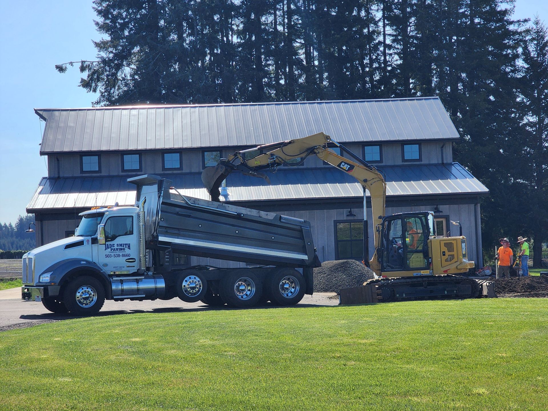 A dump truck and an excavator are parked in front of a building.