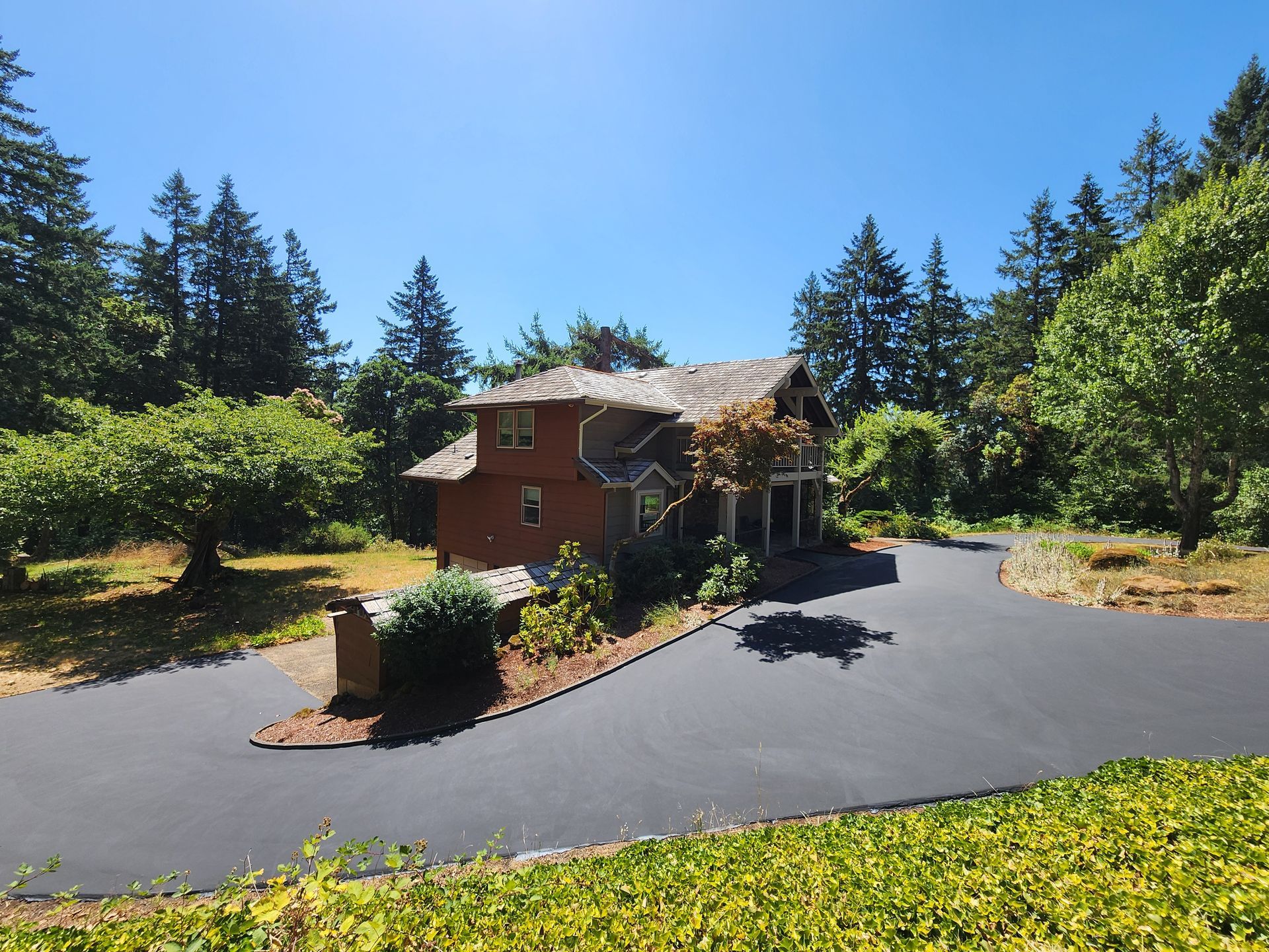 A large house is surrounded by trees and a driveway