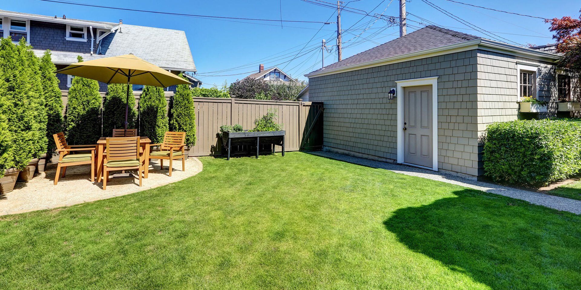 A lush green backyard with a patio area and a shed.