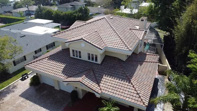 Aerial view of a house with a brown tile roof, beige walls, and a two-car garage.