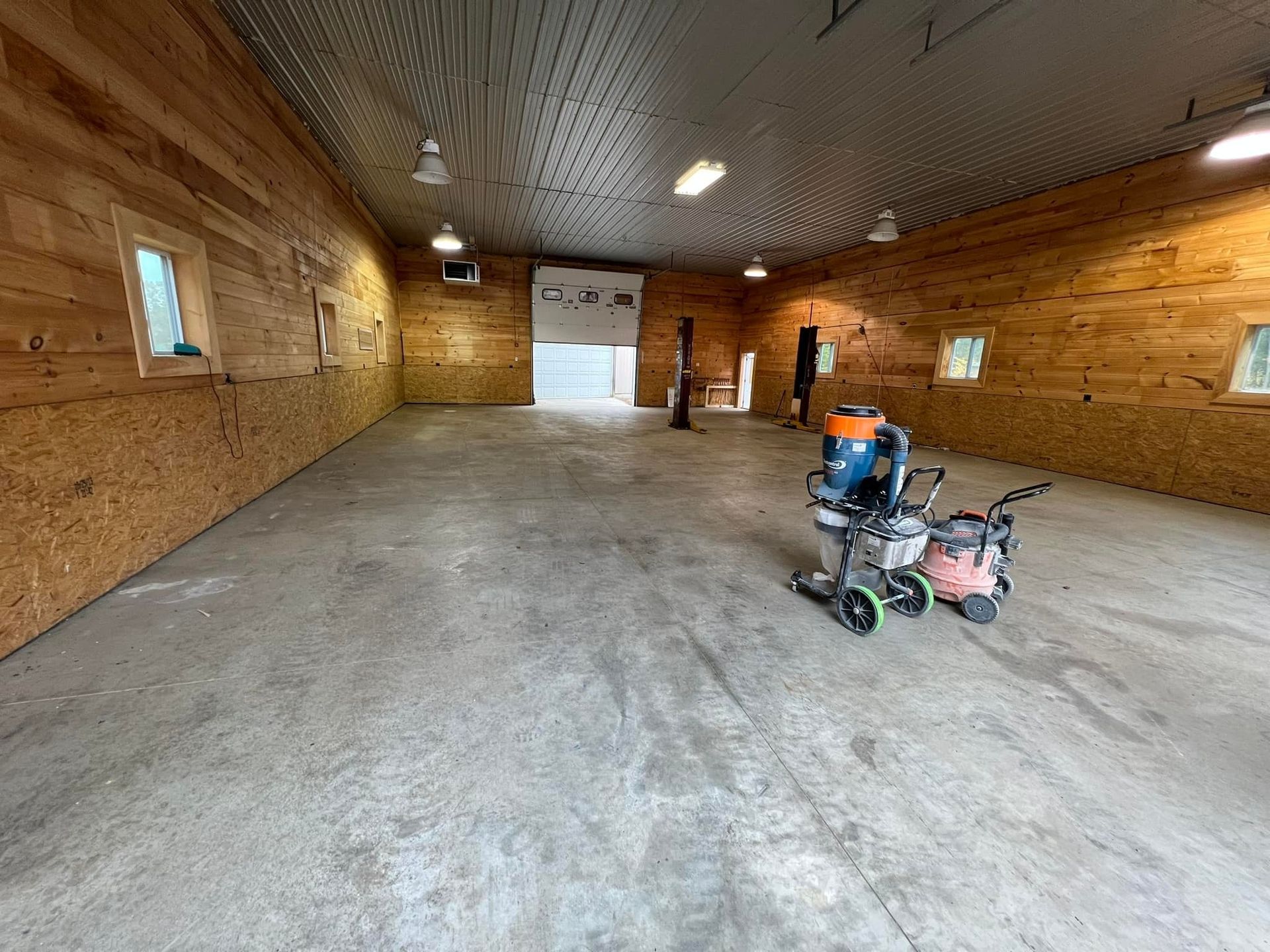 Interior of a large barn with concrete floor; a concrete grinder sits in the center.