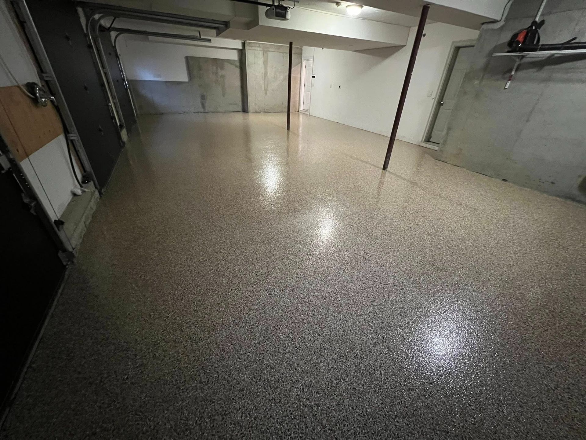 Garage with speckled epoxy floor; gray, white, and black tones. Interior shot.