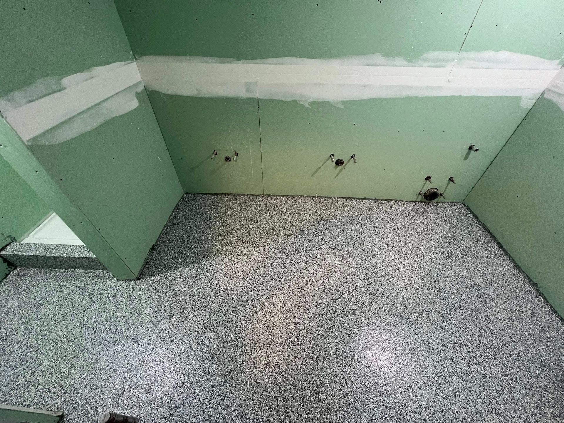 Green walls and floor covered in small, gray pebbles.