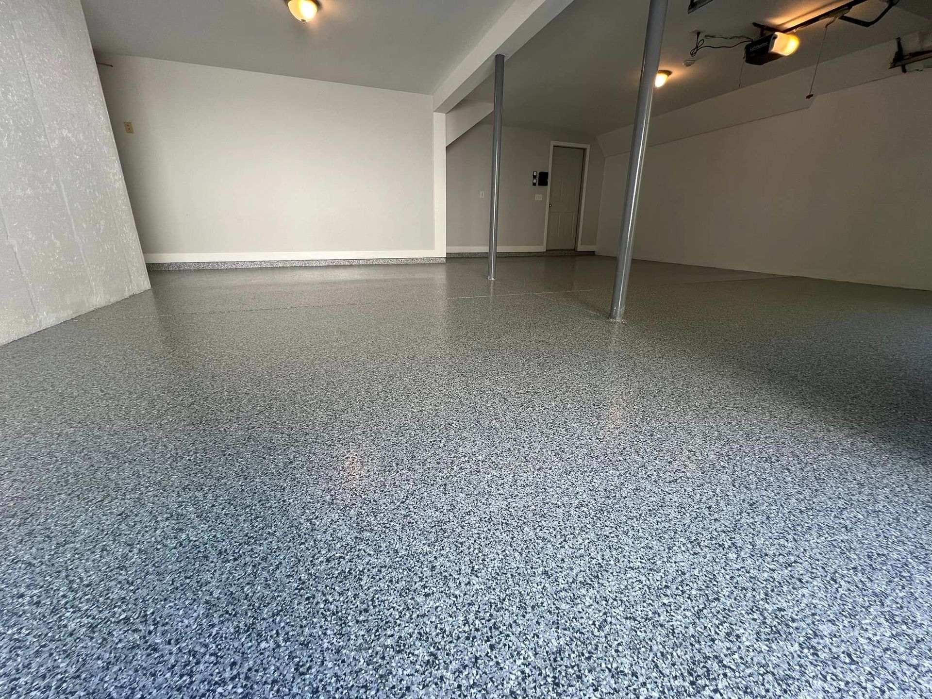 Empty garage with a speckled, epoxy-coated floor and white walls.