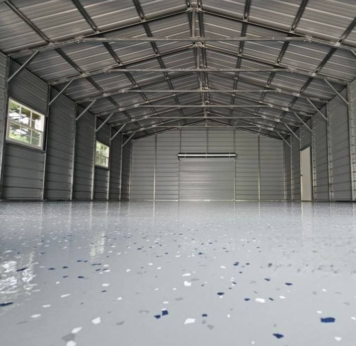 Interior of a metal shed with a shiny, speckled gray floor and empty space.