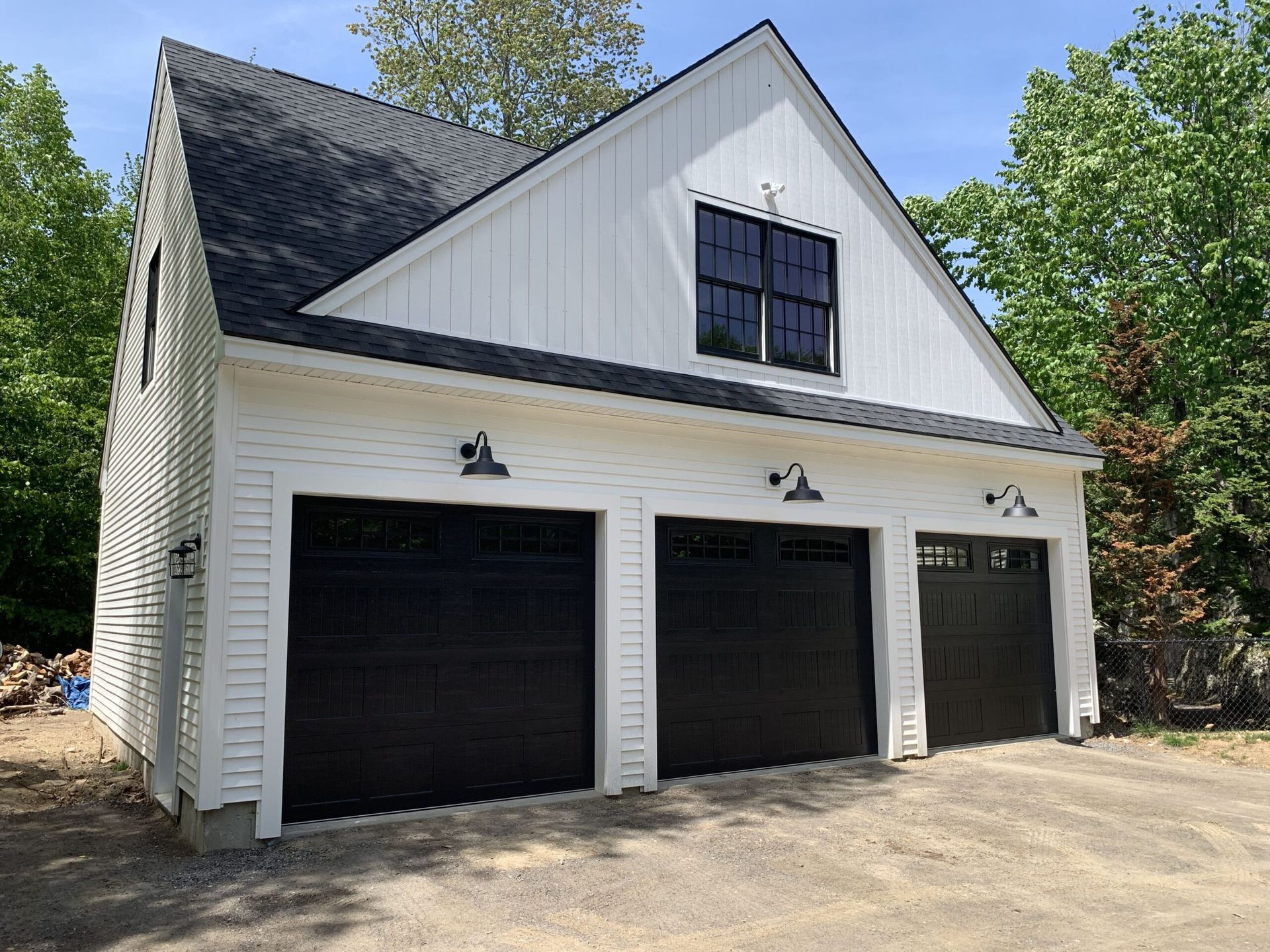 White and black three-car garage with black doors, black roof, and small window.