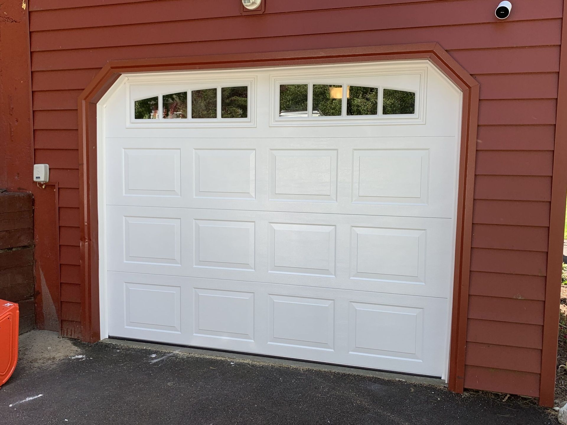 White garage door with windows, brown trim and siding.