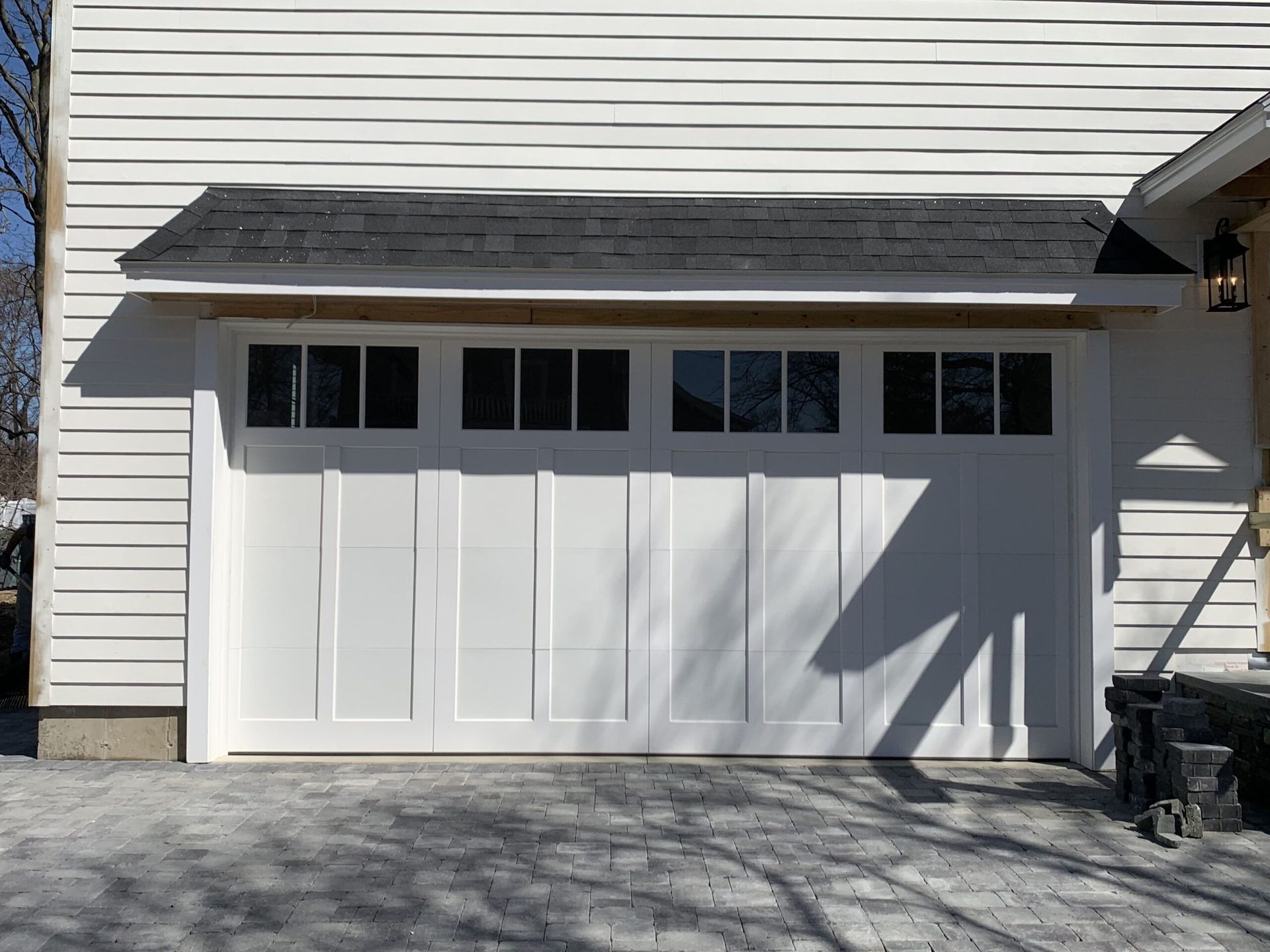 White garage door with dark trim, small roof.